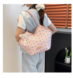 Close-up of pink tote bag with bow prints, lace pearl pendant, and leather label details
