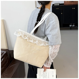 Detail of canvas tote bag featuring floral lace trim and white letter embroidery