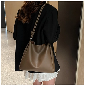 Detail of dark brown leather tote bag featuring a decorative knot on the shoulder strap