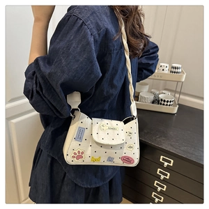 Chic white polka dot crossbody bag with colorful cartoon patches on a model's shoulder