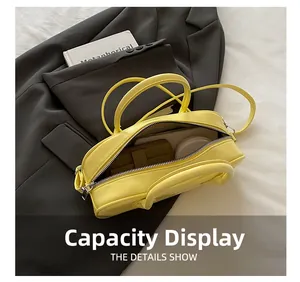 Macro detail showing spacious interior of yellow glossy leather baguette bag with essentials