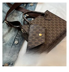 Close-up of brown monogram tote bag with gold hardware and wide woven strap details