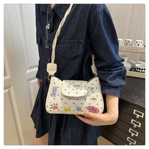 Polka dot crossbody bag with cartoon patches and woven strap shown on a model