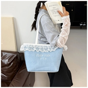 Detail of light blue canvas tote bag with delicate white lace trim and letter print