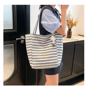 Detailaufnahme der gestreiften Canvas-Einkaufstasche mit Logo und weißem Plüschtier
