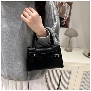Détail du petit sac noir à nœud en cuir mat avec bandoulière et boucle élégante