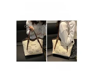 Detail of woven straw tote bag featuring cat embroidery and brown leather shoulder straps