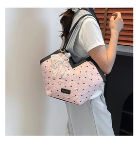 Detail of pink pleated tote bag with black bows and pearl lace pendant in use