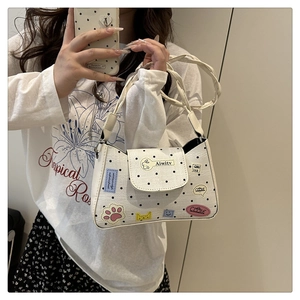 Detail of white leather tote bag with black polka dots and colorful embroidered patches