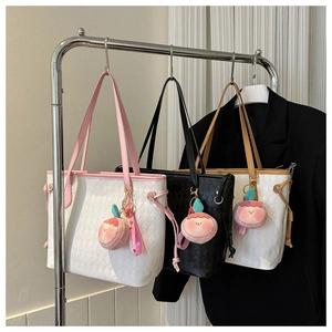 Close-up of quilted tote bags in multiple colors with cute peach plush pendants
