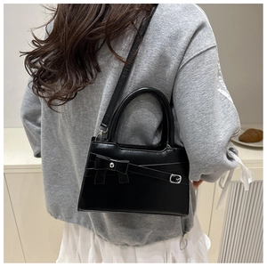 Détail d'un petit sac carré noir avec nœud élégant et fini en cuir mat