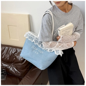 Detail of light blue tote bag with white lace trim and embroidery in a lifestyle setting