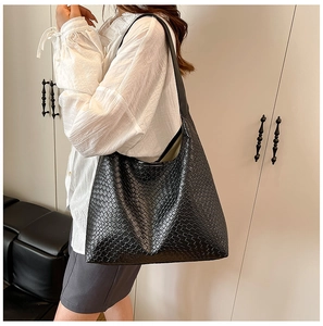 Detail of a large black woven shoulder tote bag in hobo style for casual daily use
