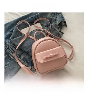 Close-up of pink mini leather backpack with bow detail and comparison to mobile phone