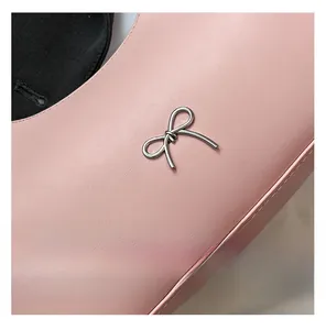 Close-up of pink litchi-textured leather shoulder bag with silver metal bow detail