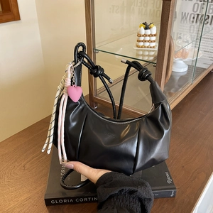 Minimalistische schwarze Leder-Croissant-Tasche mit Prägung und Herzanhänger-Detail