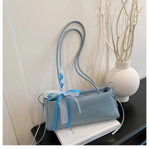 Détail du sac à bandoulière bleu clair brillant avec nœud en dentelle et ruban