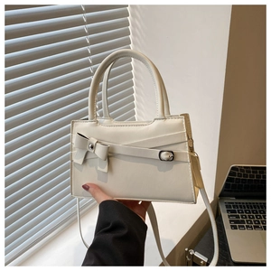 Détail d'un sac à main blanc crème avec nœud papillon et boucle métallique