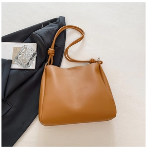 Detail of tan brown PU leather tote bag with unique knotted strap on a minimalist background