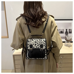 Detail of leopard print mini backpack with leather trim on model wearing a trench coat