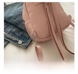 Detailed close-up of the silver D-ring and lobster clasp on this pink bow square bag