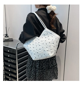 Detail of white quilted nylon tote bag with black bows and fashion metal plaque