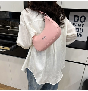 Close-up of pink hobo shoulder bag with a silver metal bow accent and smooth leather