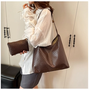 Detail of dark brown woven texture hobo bag and small clutch set held by a model