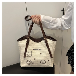 Detail of straw tote bag featuring cute cat embroidery and premium leather handles