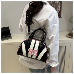 Detail van een sportieve zwart-witte crossbodytas met roze 96 patch en stervormige klinknagels