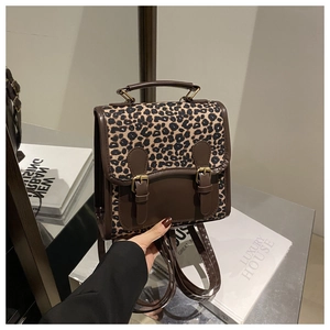 Close-up of leopard print backpack with dark brown leather trim and dual buckle closure