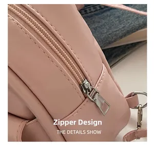 Close-up of a pink shoulder bag showing smooth synthetic leather and a metal zipper detail
