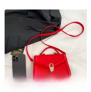 Sac bandoulière rouge avec fermoir doré et smartphone pour comparer la taille