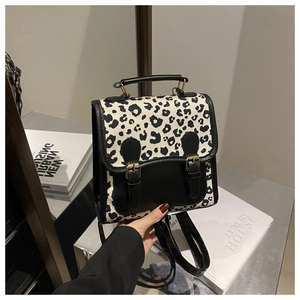 Detailed view of the leopard print travel backpack with black leather flap and buckle closure