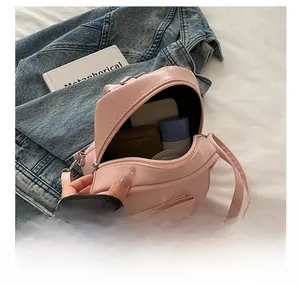 Pink PU leather bag showing internal storage capacity with phone and wallet inside