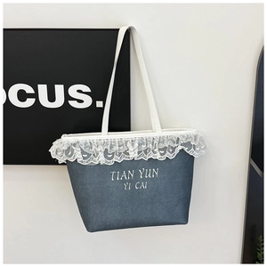 Détail de la dentelle blanche et lettrage imprimé sur un cabas d'été bleu denim