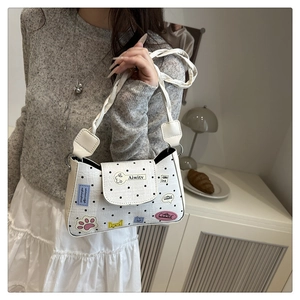 Close-up of white polka dot shoulder bag with cute patches and woven handle detail