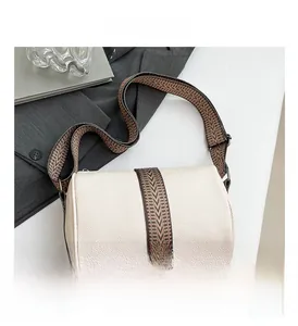Detail of cream lychee leather cylinder bag with textured geometric woven wide strap
