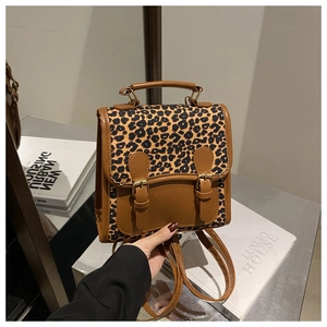 Detail of leopard print backpack with brown leather trim and vintage metal buckle closure