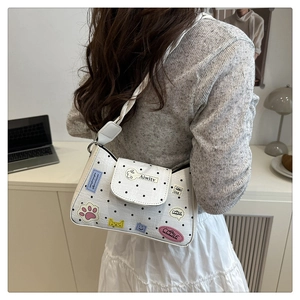 Polka dot shoulder bag with cartoon patches worn by a model in a cozy room setting
