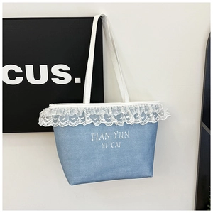 Détail du sac cabas en toile bleu clair avec bordure en dentelle et anses en similicuir