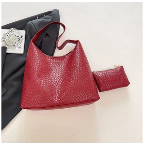 Detail of dark red woven hobo bag and matching pouch on a cream textured background