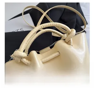 Detail shot of the cream bucket bag featuring a unique knotted top handle design
