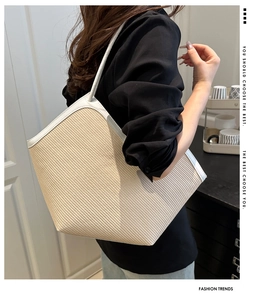 Detailed close-up of woven straw texture and white leather handles on a summer tote bag