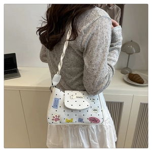 Detail of white polka dot tote bag with cute cartoon patches and woven shoulder strap