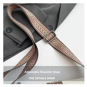 Detail of adjustable woven shoulder strap with ethnic geometric patterns on a grey blazer