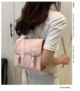 Detail view of pink leather backpack featuring lace bow decoration and stylish flap design