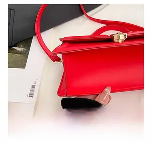 Vue détaillée du sac en cuir rouge avec coutures précises et fermoir rotatif doré élégant