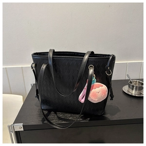 Detail of black tote bag with quilted texture and pink peach plush charm decoration