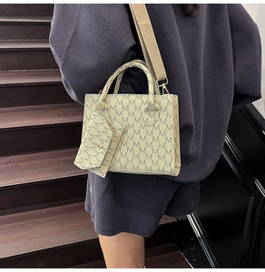 Close-up of vintage tote bag set with monogram print and wide woven shoulder strap